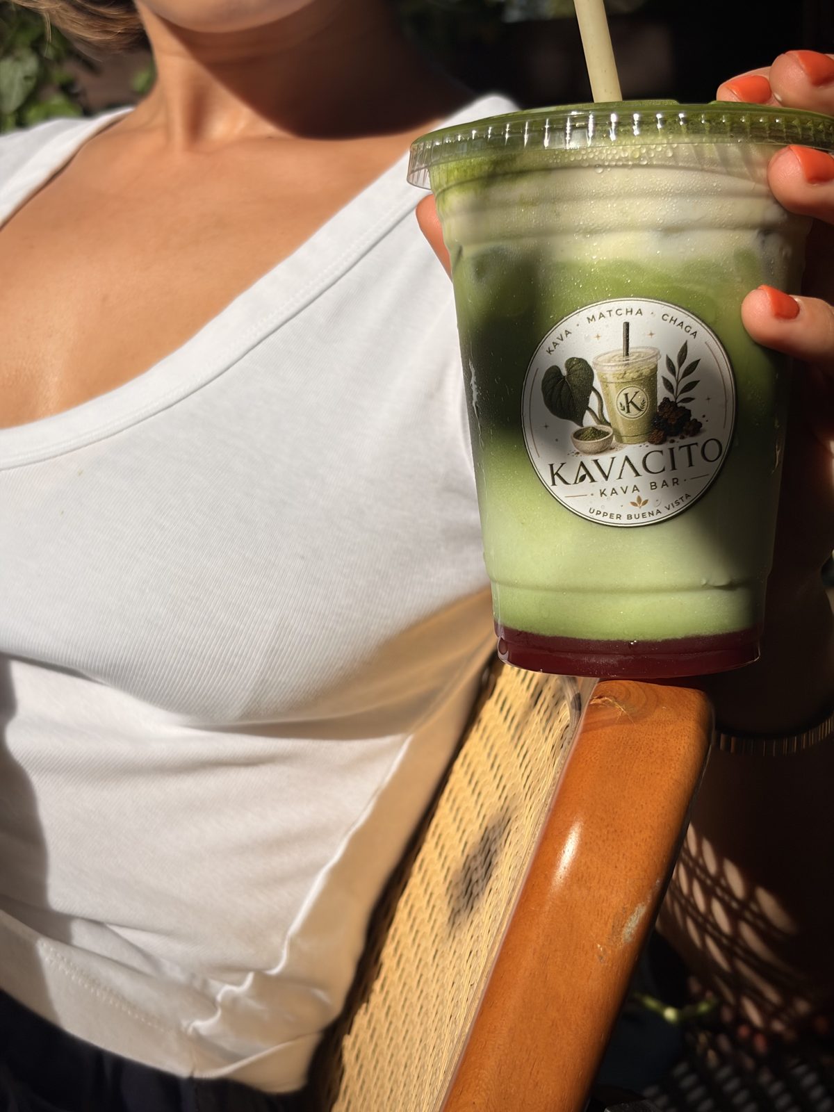 A guest holding a Kavacito matcha latte in the afternoon light